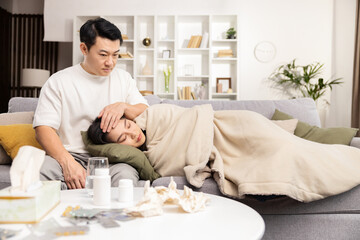 Caring man comforts sick woman on couch with medicine and tissues, depicting care, sickness, and...