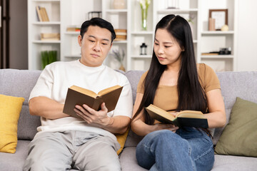 Couple Reading Books Together On Sofa, Serene Home Leeisure, Quality Time, Educational Activity, Relaxed Atmosphere, Adult Education, Casual Enjoyment, Asian Couple Leisure Time, Reading Session. 