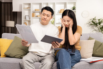 Asian Couple Managing Finances, Worried Woman With Tablet, Concerned Man Reading Documents, Home Budget Planning, Financial Stress, Couch, Living Room