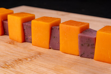 Cubes of orange and lavender cheese, alternating, lie on the table.