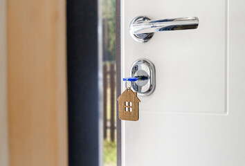 a key with a keychain in the shape of a house is inserted into the door lock