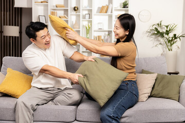 A joyful couple engaging in a playful pillow fight in their cozy living room, radiating happiness and love.
