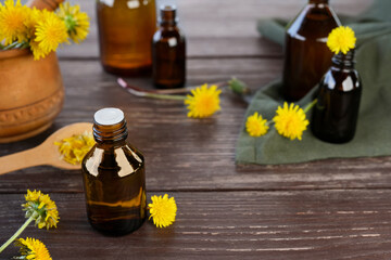 Bottle of essential oil with flowers dandelions. Healing herbs. Dandelions tinctures. Concrept of herbal or homeopathy medicine.  Herbal medicine. Side view. Space for text.