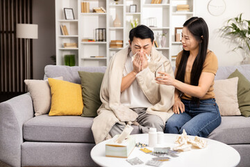 Caring woman comforting sick man on couch, cold flu care, home remedy, couple indoor