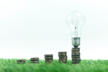 A stack of pennies on a green field with a light bulb on top