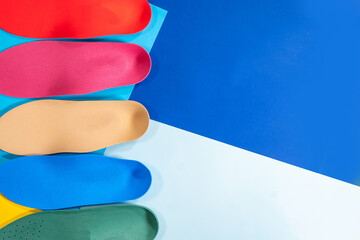 Orthopedic insoles for shoes on a colour background. Foot care