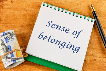 Business, sense of belonging concept. Text Sense of belonging on a notepad near money and a...
