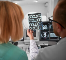 Medical computed tomography or MRI scanner. Back view of doctor and nurse sitting at computer,...