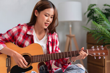 Concept of relaxation with music, Young asian woman practice playing chords with acoustic guitar - 784334418