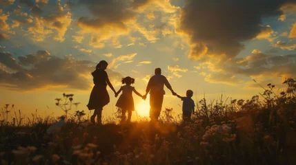 Fotobehang In the general plan, against the background of the sunset sky, silhouettes of a family with two young children move from left to right, everyone holds hands and merrily walks and leaves the frame © Plaifah
