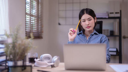 Young asian student women studying to watching lecture webinar in online class on laptop and thinking educational to taking note while doing homework and learning knowledge remote education from home - 784335255