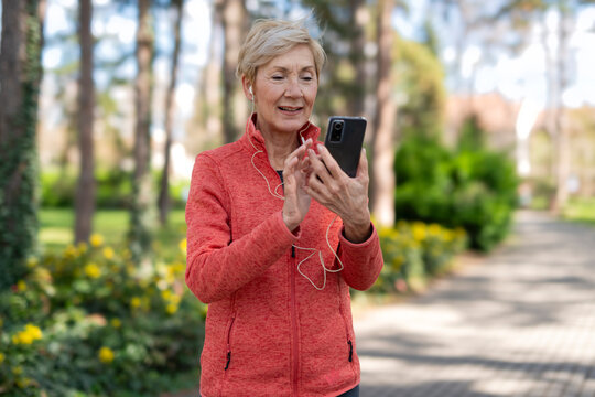 Senior woman, fitness and music earphones for workout, training or exercise in nature park