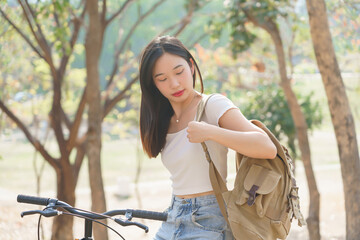 Young asian women sitting on bicycle and carrying backpack to preparing for cycling bicycle in the nature park while having happiness and relaxation with journey travel trip for healthy lifestyle