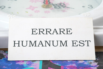 Latin quote Errare humanum est, meaning It is human nature to make mistakes. Mistakes are inherent in human existence. Text written on a white business card