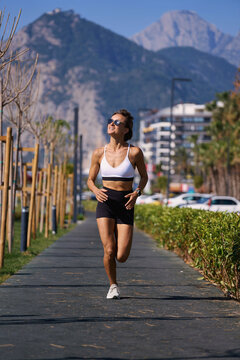 Female runner running at morning in city park. Healthy fitness woman jogging outdoors. Mountains in background. High quality photo