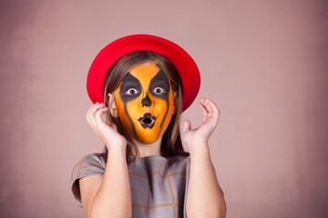 Pretty girl with face painting of a pumpkin