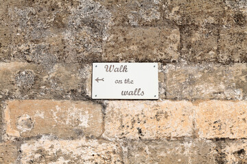 Cartello con indicazioni su vecchio muro
