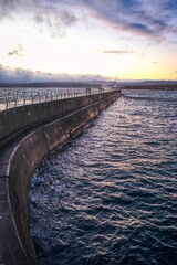 Vertical shot of a big breakwater in Victoria, British Columbia with a lighthouse on the horizon