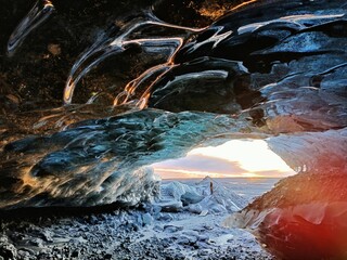 Ice cave of the Katla volcano with the sunset in the background in Iceland © Wirestock