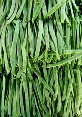 Vertical shot of green beans stacked in an outdoor maket on a sunny day