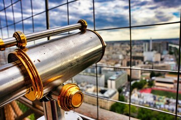 Closeup shot of a telescope behind metal bars with Paris city in the blurred background