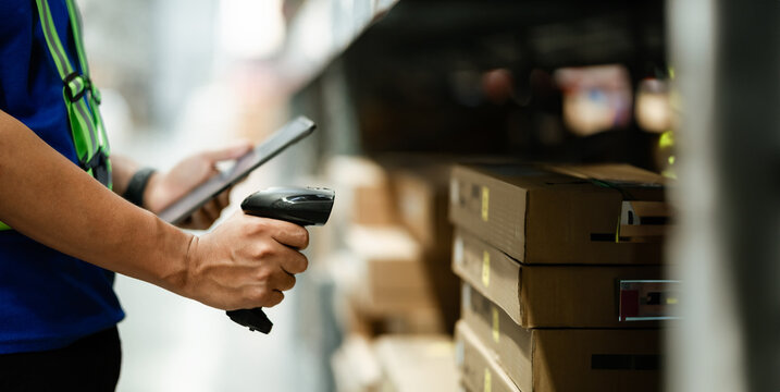 A person is scanning a barcode with a tablet. The person is wearing a green vest. Concept of efficiency and organization in a warehouse or store setting