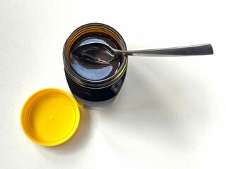 Top closeup of a newly opened yeast extract marmite jar with a spoon in it, white background