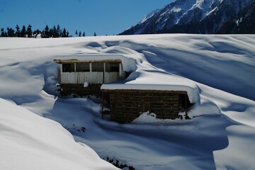 View of buildings covered in snow on a sunny day in the mountainside