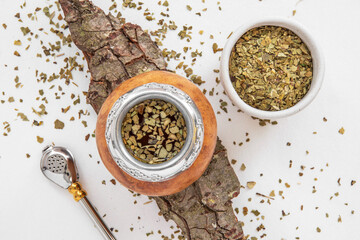 Mate tea in a typical South American calabash, with dried leaves next to it - 784350204