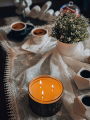 Top view of beautifully arranged cups of coffee on a tablecloth decorated with flowers and candles