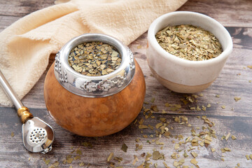 Mate tea in a typical South American calabash, with dried leaves next to it - 784350273