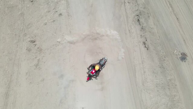 Aerial drone view of a man on a motorcycle drifting on the sand