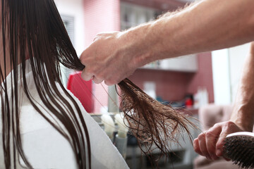 Hair care in a beauty salon. Tangled long hair. A woman with tangled dark hair.