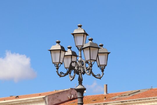 Pole with street lamps against a cloudy blue sky