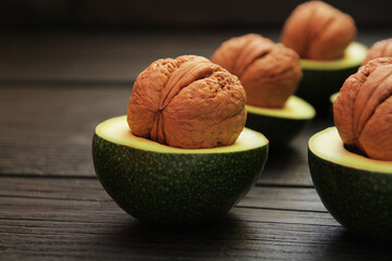 The concept of food combination. Fresh avocado fruits are cut in half and walnuts are inserted in...
