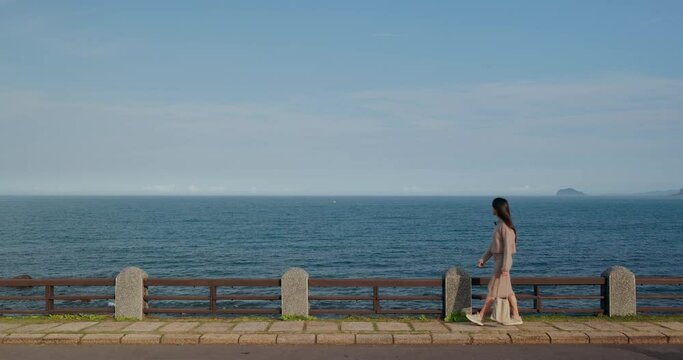 Woman walk along the waterfront with the blue sea in north coast in Taipei