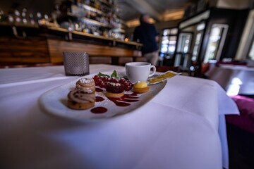 Set of cookies with berries and a cup of tea on a white plate in a cafe