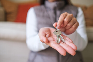 Closeup image of a woman holding and giving the keys for real estate concept