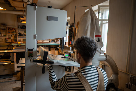 Male carpenter holding digital magnetic inclinometer with level, adjust angle of saw before working. Man using horizontal angle meter to align blades and fences on table saw at workshop. Woodwork.