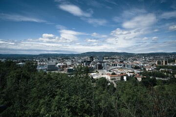 Cityscape of Oslo surrounded by greenery under a blue cloudy sky in Norway