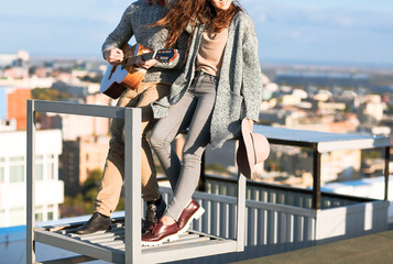 Young man and woman embrace and playing music outdoors