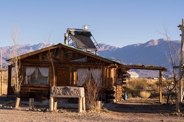 Solar panel on the roof of a wooden cottage in a semi-desert area with mountains in the background