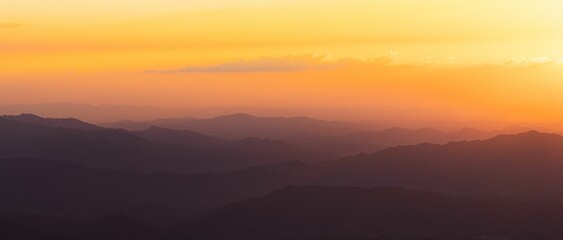 Obraz premium Beautiful view of a sunrise over the silhouettes of the mountain range