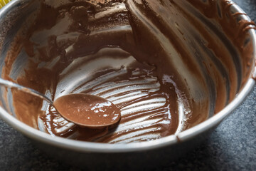 Dirty metal mixing bowl being used to prepare chocolate cupcakes - obrazy, fototapety, plakaty