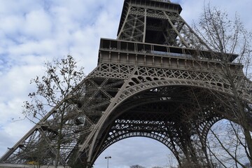 Low angle shot of the famous Eiffel tower in Paris against the cloudy sky during the daytime