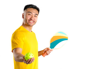 young oriental man smiling with yellow t-shirt and pickleball paddle and ball on white background