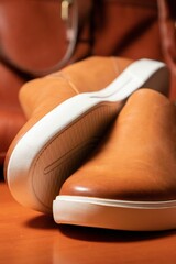 Vertical shot of a pair of brown solid slip shoes over the wooden table