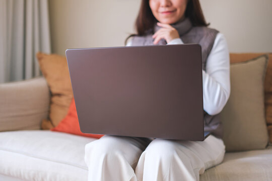 Closeup image of a young woman working on laptop computer at home