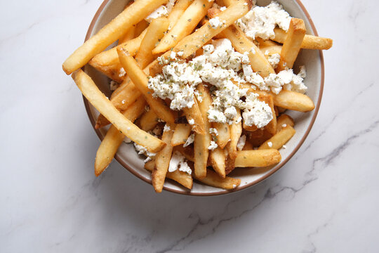 Bowl of hot chips with sprinkled feta cheese