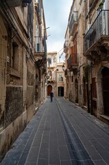Fototapeta na wymiar Vertical shot of a historic alley with old buildings in Syracuse, Sicily, Italy